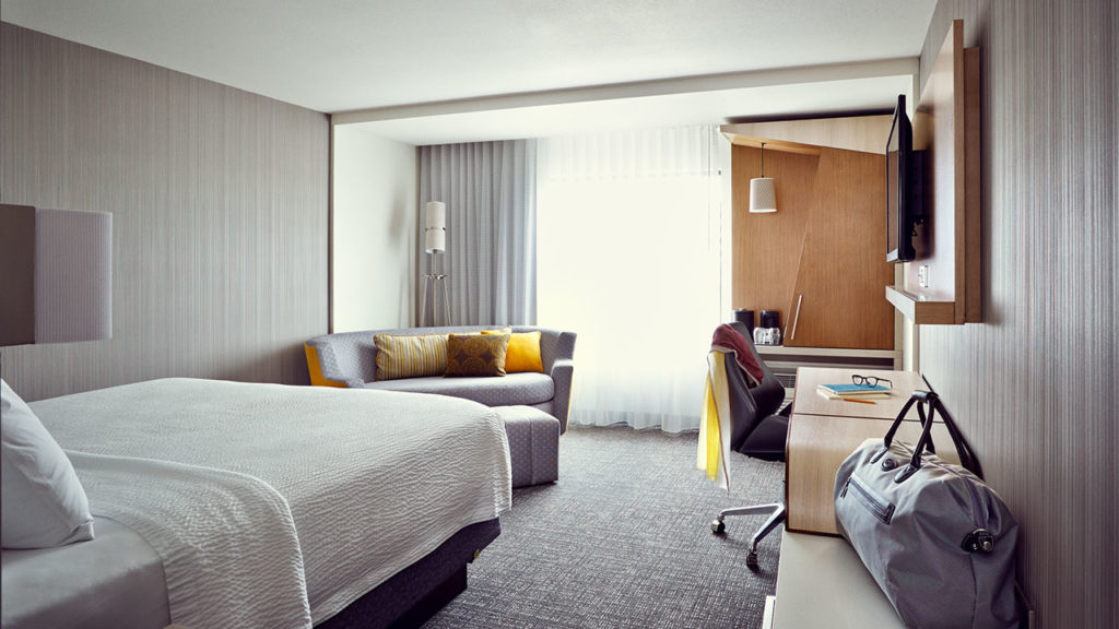 crisp, clean, up-scale hotel room with white sheets, modern sofa and furniture