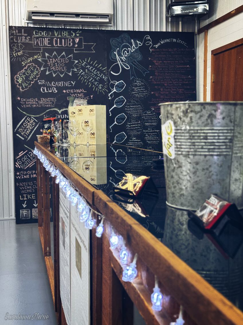 Wine tasting counter in front of a chalkboard wall with wine club details.