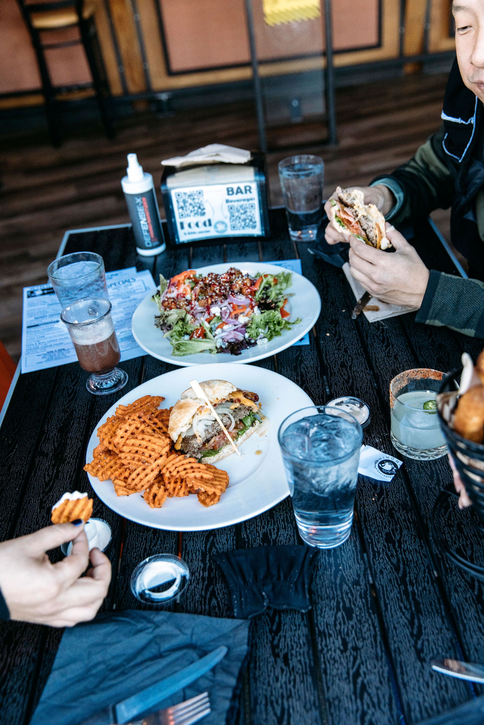 People sitting at a table eating a burger with fries and a salad