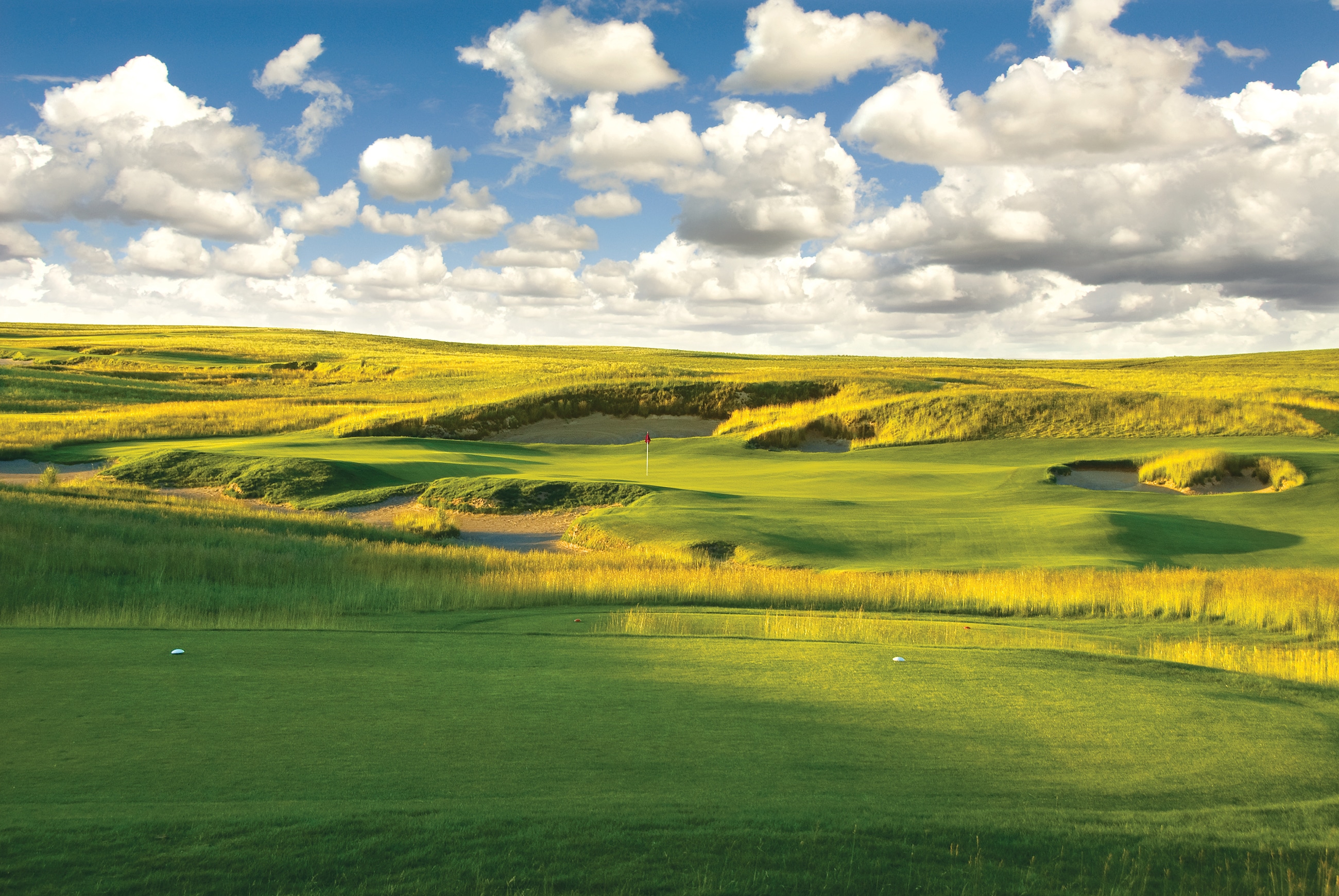 green fairway, links-style rough blue sky and clouds