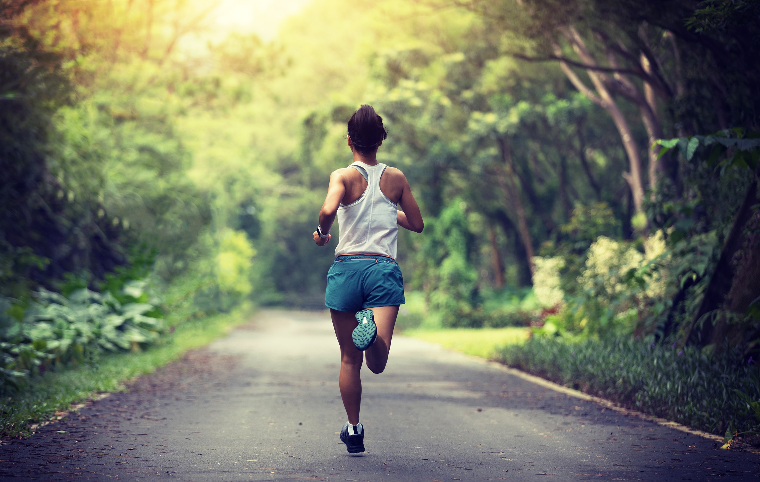 Female runner running at summer park trail